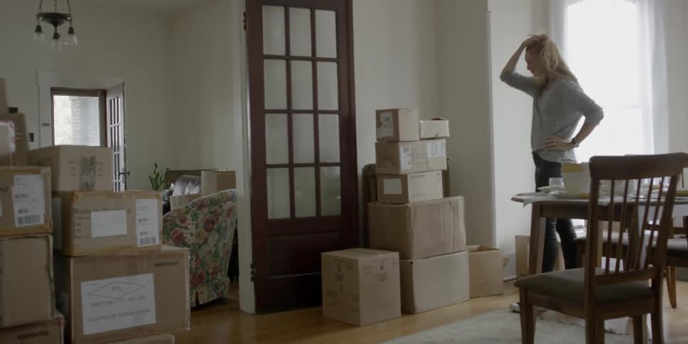 A woman stacks boxes inside a home
