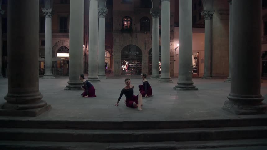 Three ballerinas dancing in between pillars