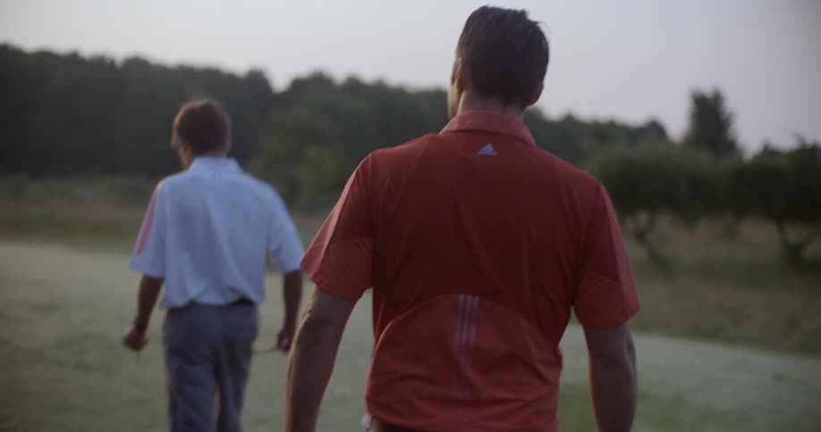 A man and boy play golf at sunset