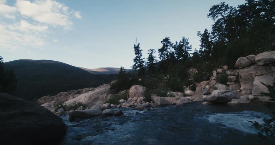 A river lined with rock and boulders in a hilly countryside during the day