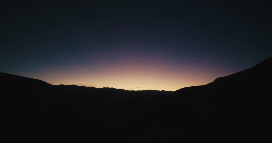 A mountain ridge shrouded in shadow at sunset