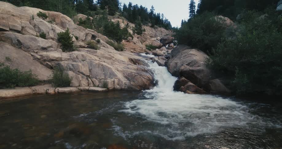 A stream flows down a rocky slope into the river below