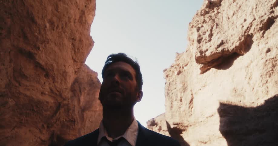 A man is slowly walking and looking up in a canyon