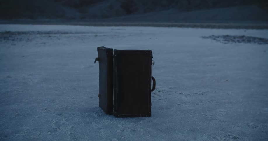 Open suitcase sits on its side in arid desert near hills
