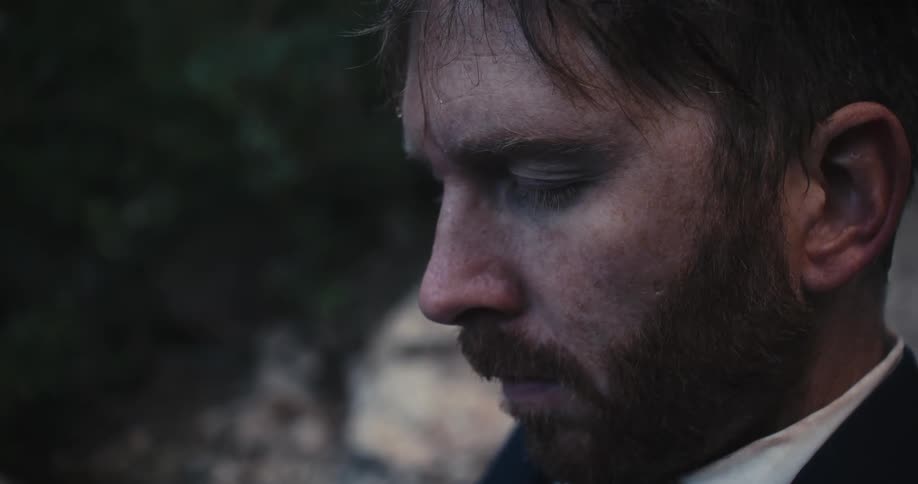 Man trembling with eyes closed in wilderness opens his eyes