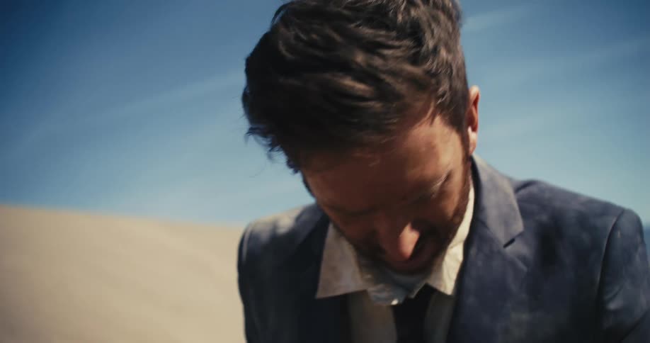 A man turns around looking through something in the desert