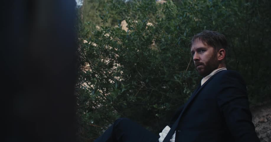 A man is wearing a suit and sitting outdoors during spring