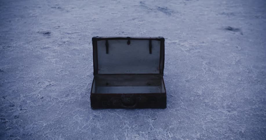Close up of an open briefcase on the ground in the desert