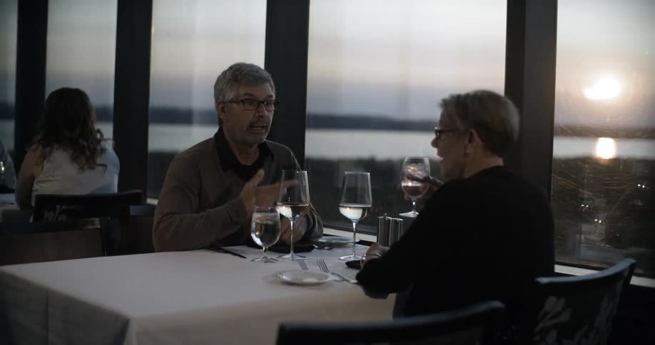 Two people are sitting down to drinks while talking