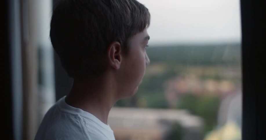 A boy looks out of a hotel window