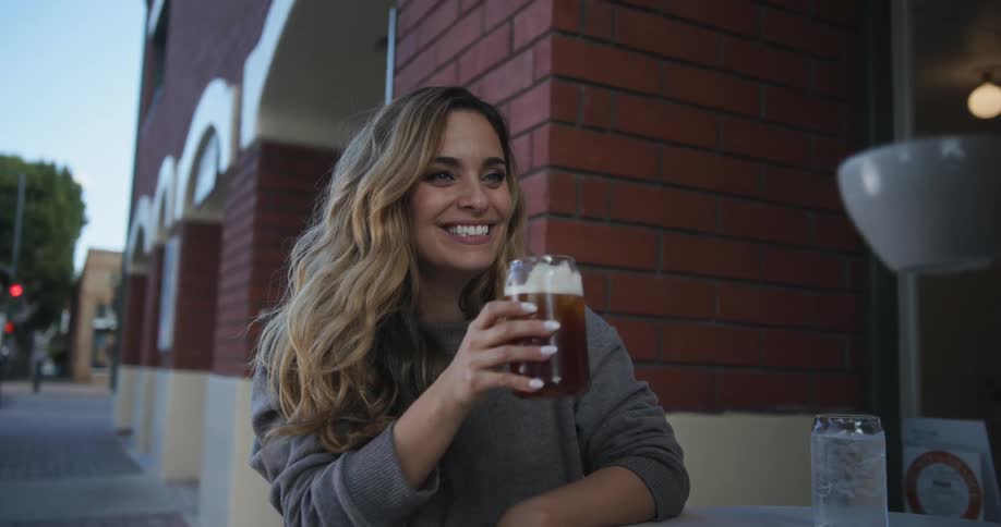 A couple sitting outside of a restaurant toasting each other