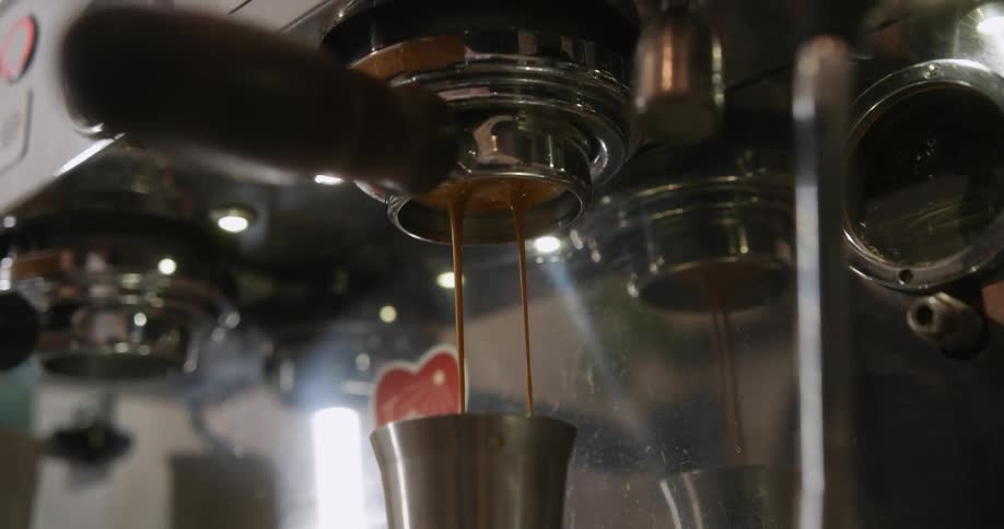 Coffee dripping from a coffee machine into a metal cup