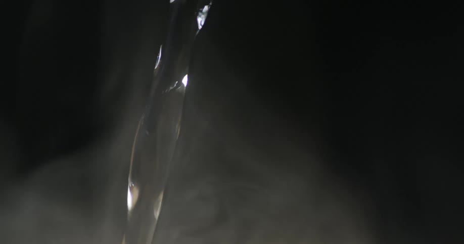 Steam rises as hot water pours from the spout of a silver teapot