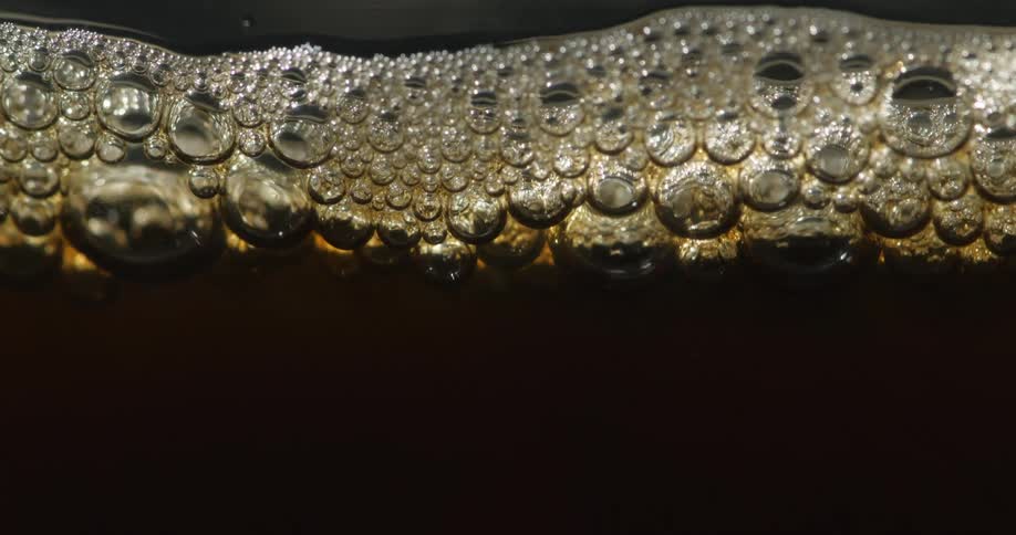Soap bubbles on surface of liquid bob up and down against glass