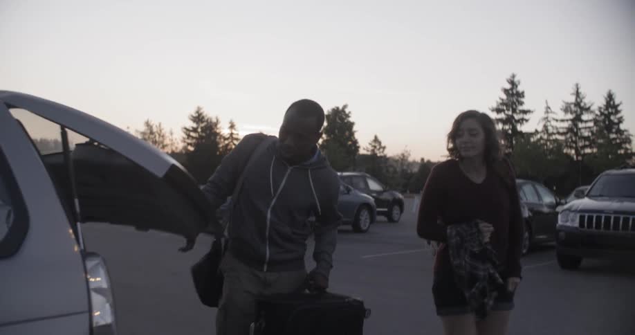 A man and woman remove luggage from an suv