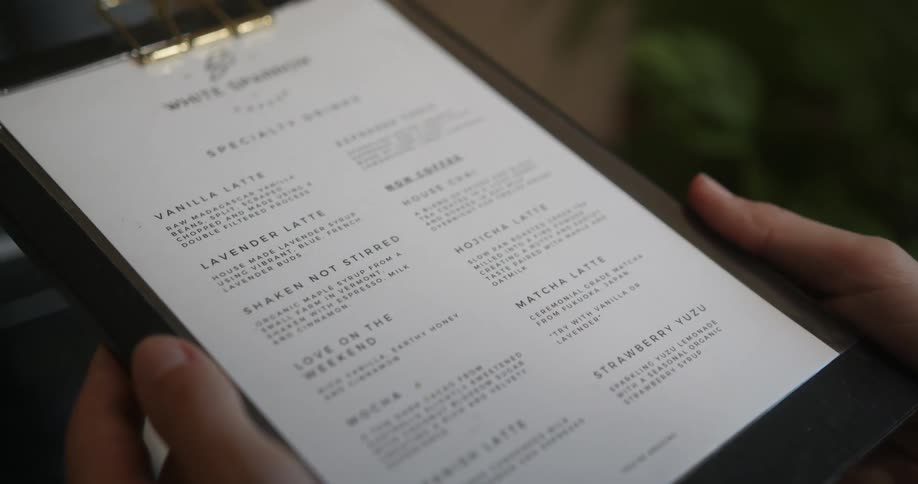 A waiter is holding up a menu at a restaurant that is inside