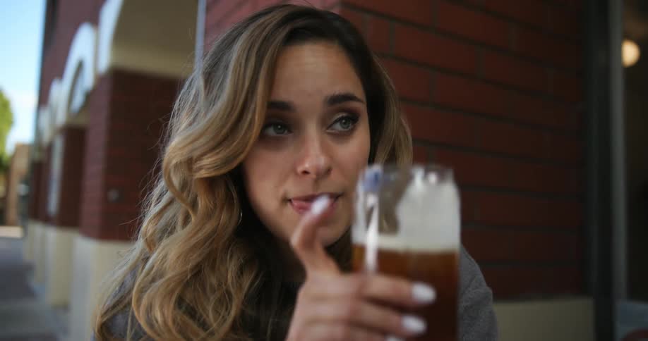 Woman smiles while she sips and talks with man at outdoor table
