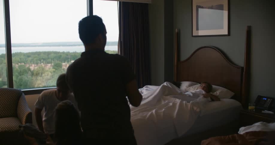 A man throws an object at a person sleeping in bed waking him