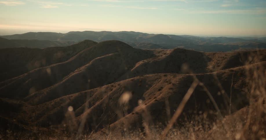 Grass covers hills stretching to the mountains on the horizon