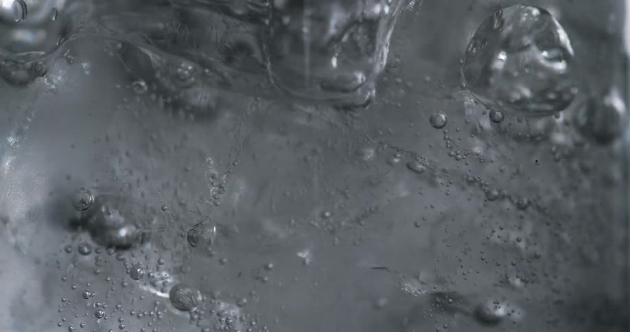 Close up of sparkling water filling up a glass filled with ice cubes