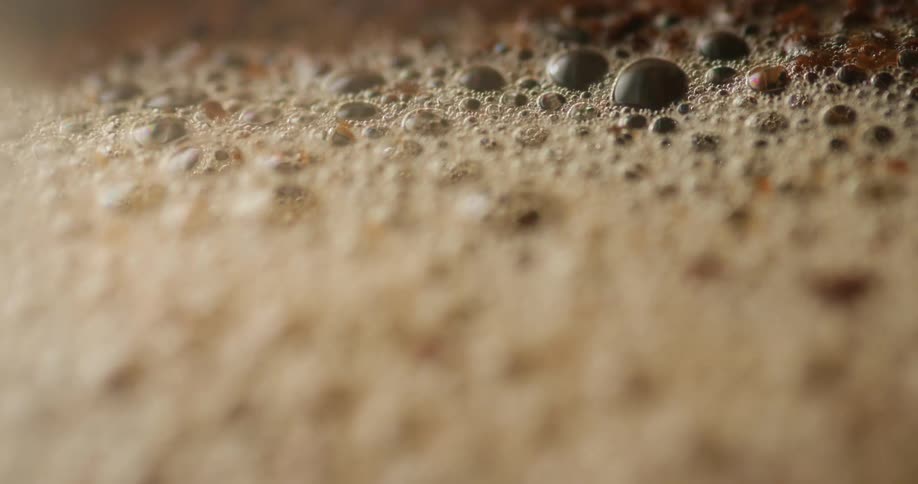 Extreme close up of steaming hot water pouring over ground coffee