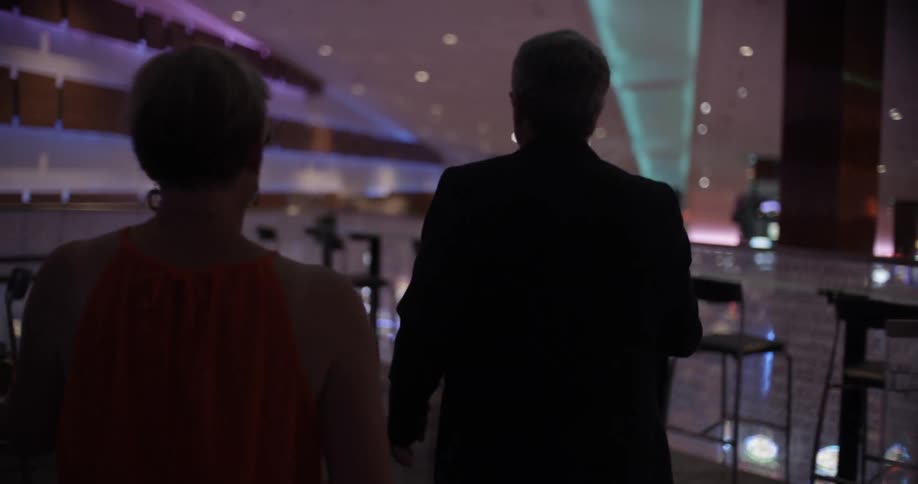 A man and a woman walk towards a table while holding drinks