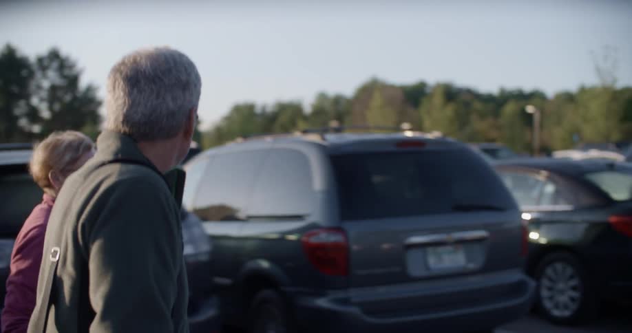 A man and woman walk in a parking lot