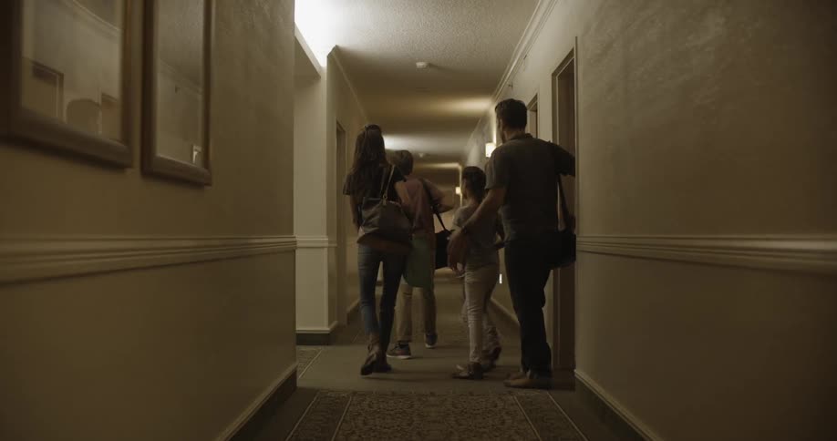 A family walks out of their hotel room into the hallway
