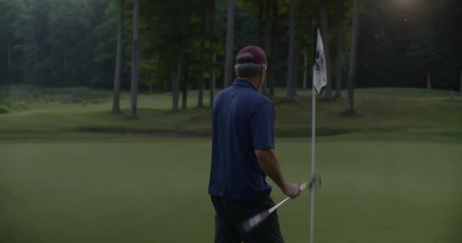 A man pulls the flag from a golf hole