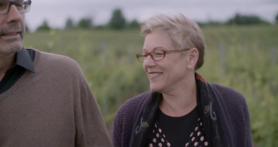 A man and woman walk in a field on a breezy day