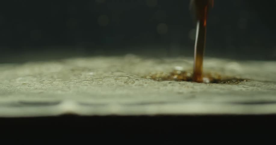 Stream of coffee fills container creating foam on the surface