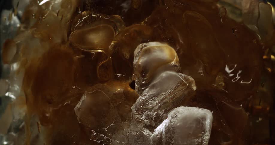 Beverage is poured into glass filled with ice cubes