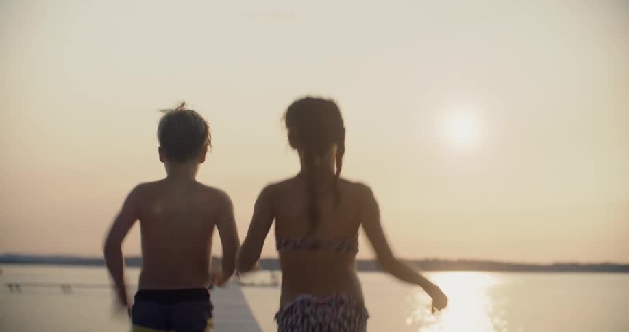 Two children run on a dock