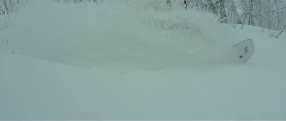 A man snowboards down a snowy hill