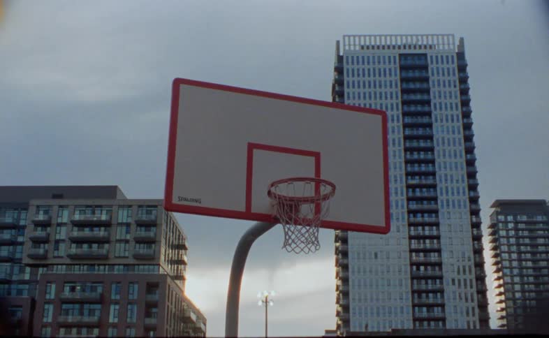 A basketball hoop on an outdoor court in a metropolis on a cloudy day