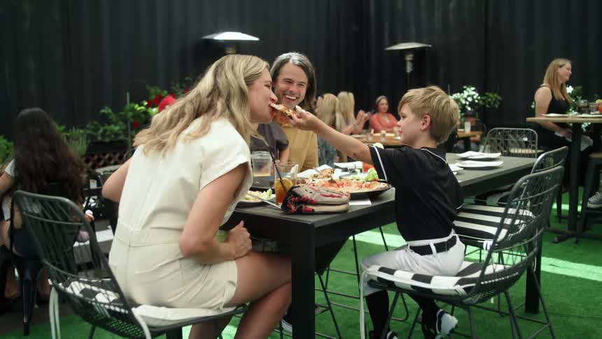 Boy shares a slice of pizza with his mother while eating lunch at a restaurant