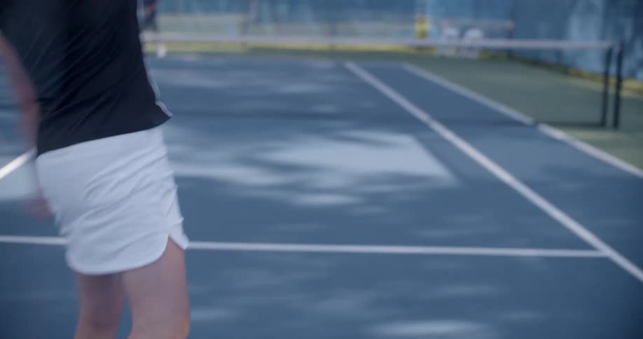 Two people playing tennis during the day
