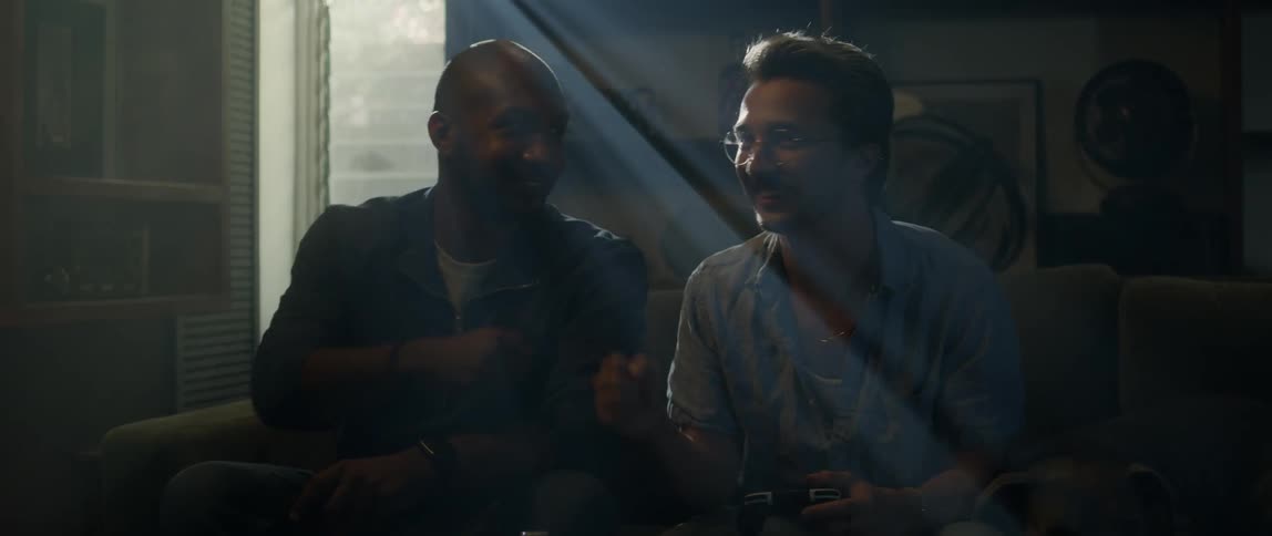 A pair of men fist bump while playing video games together in the living room of a house during the day