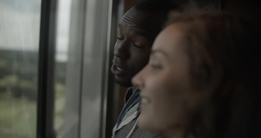 A man and woman talk in front of a window