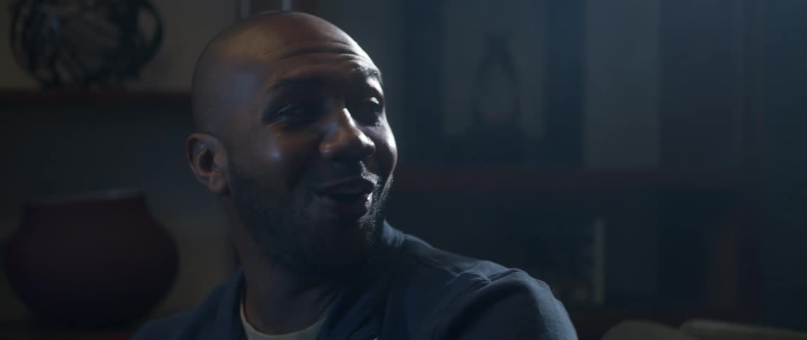 Two men talk and laugh while watching something