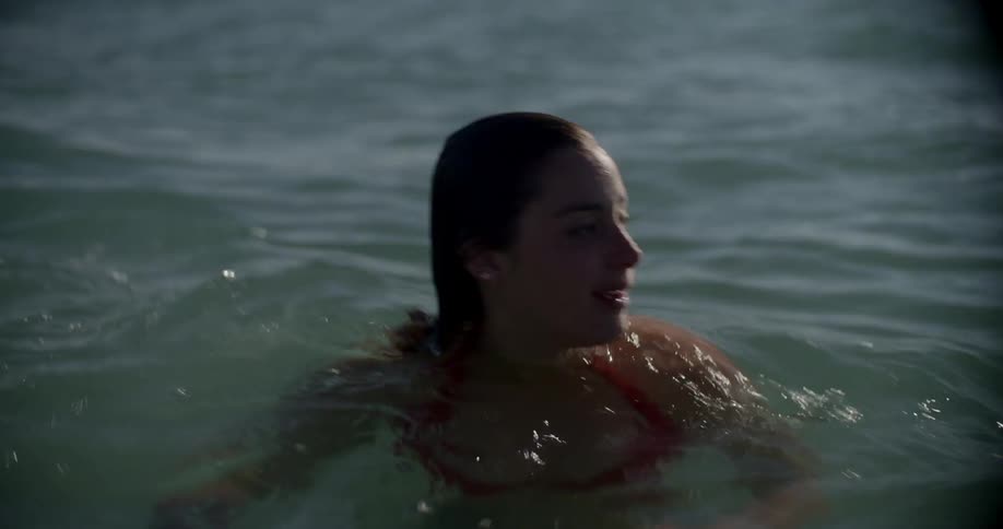 A woman rubs her nose while swimming
