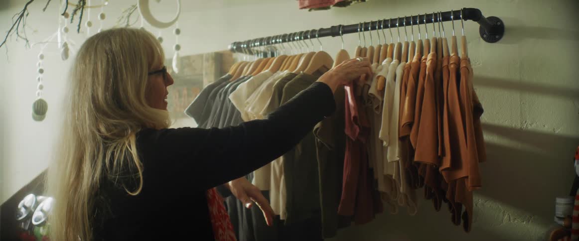 A woman putting shirts on a rack in a store