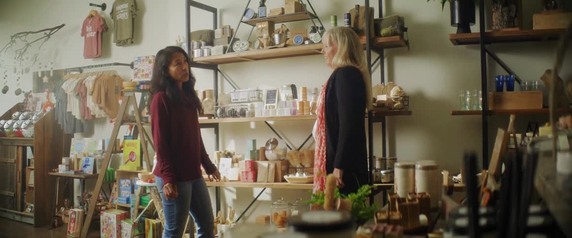 Woman discusses merchandise with sales clerk while standing in store