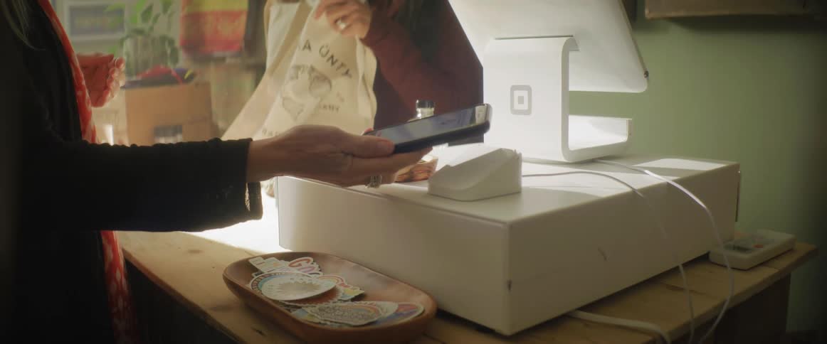 Woman uses her phone to pay for a purchase on a shop