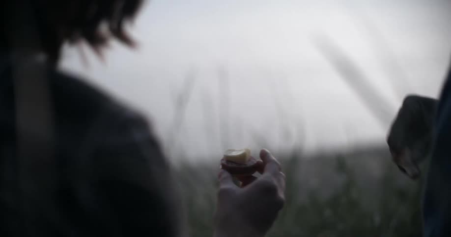 A person makes a sandwich cracker outside