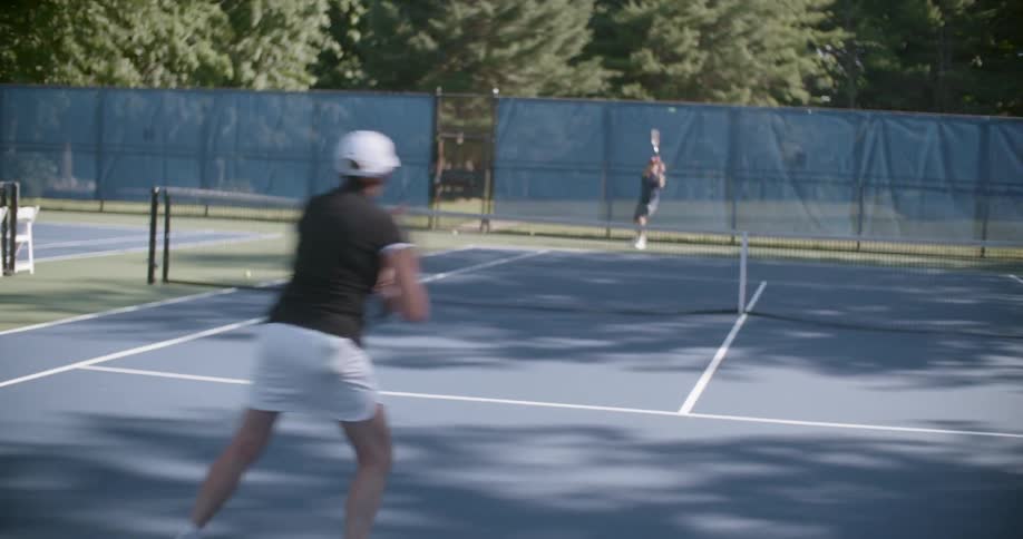 A man and woman play tennis during the day