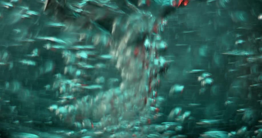 Glitter and bubbles are moving in in the liquid of a rapidly turning vortex