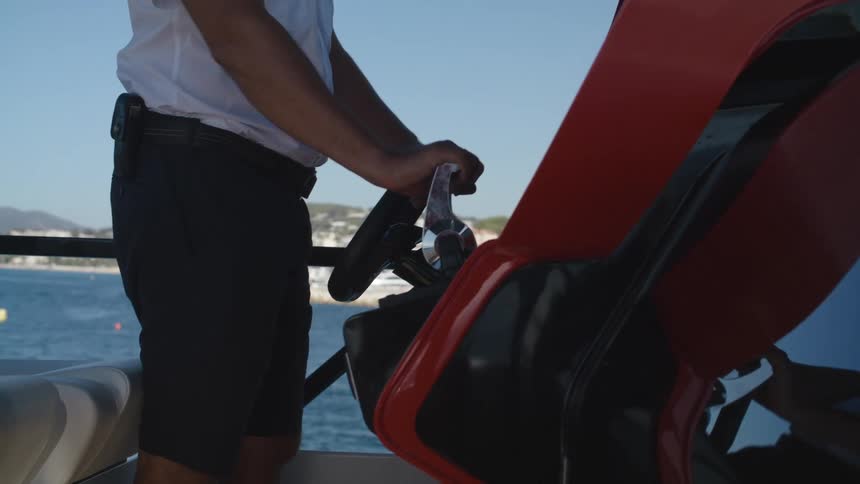 Man in white shirt and black shorts drives boat traveling on ocean water