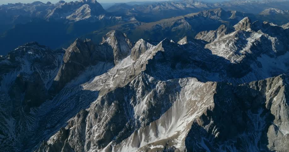 The sun shines on snow covered mountains under a clear sky