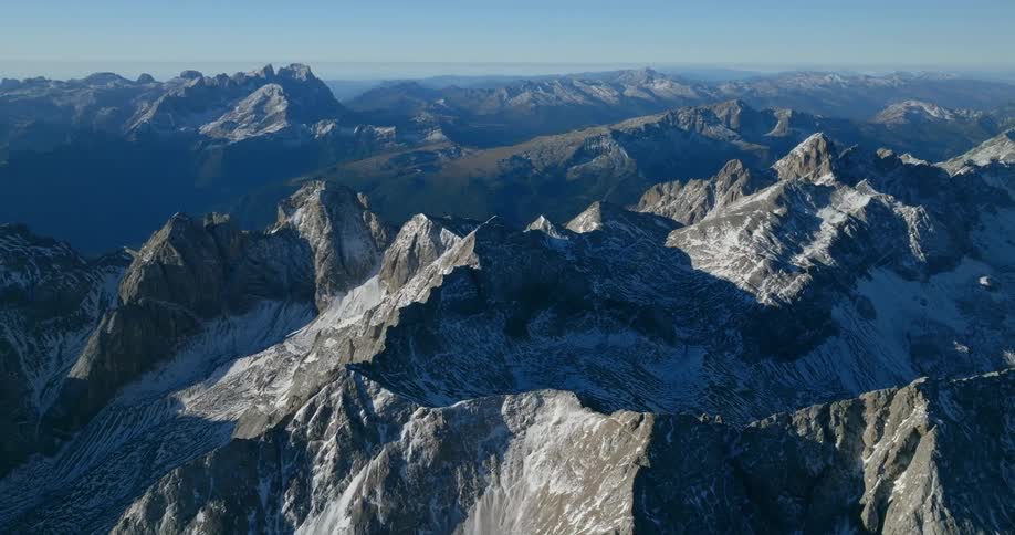 Front surfaces and tops of central mountains are lit by sunlight as remainder is is misty shadow
